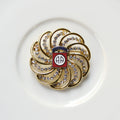 Decorative brooch with gold and red design on a white background