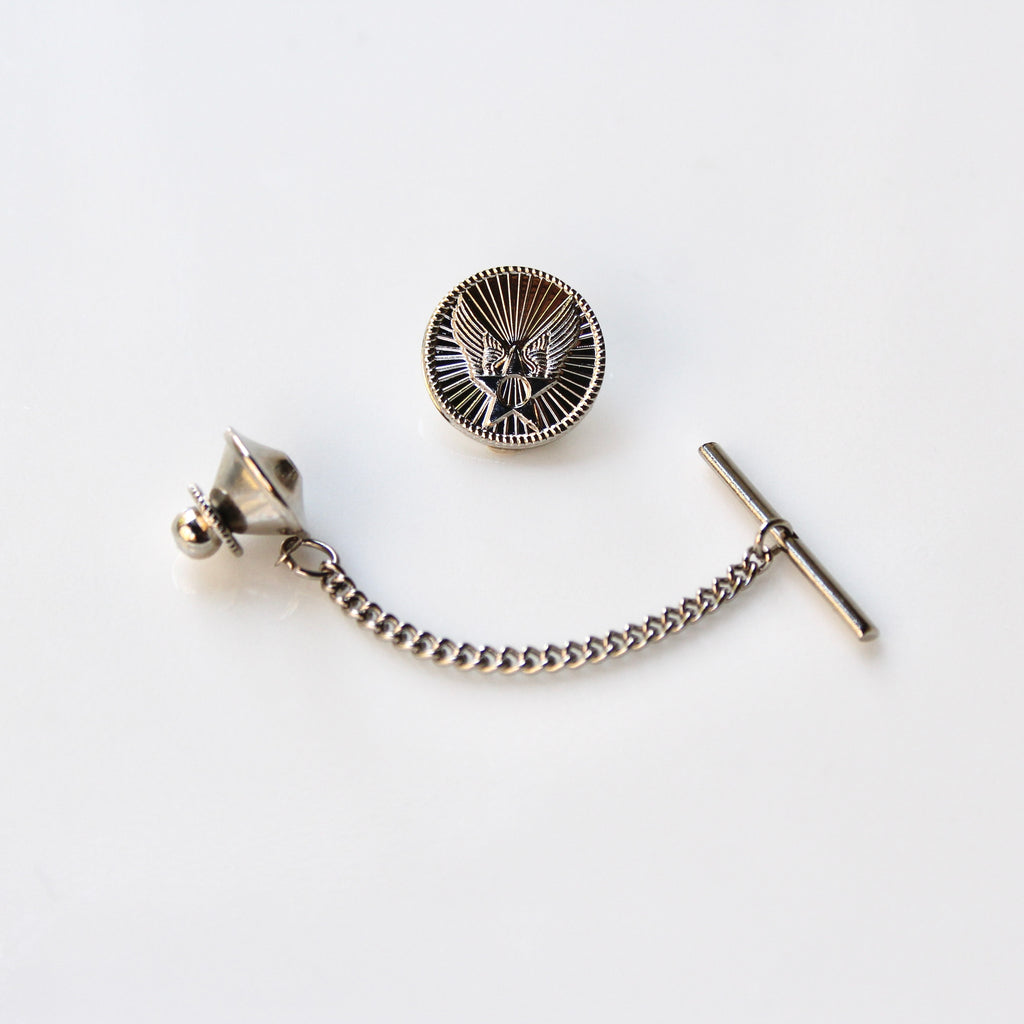 Silver tie pin with chain and eagle emblem on a white background