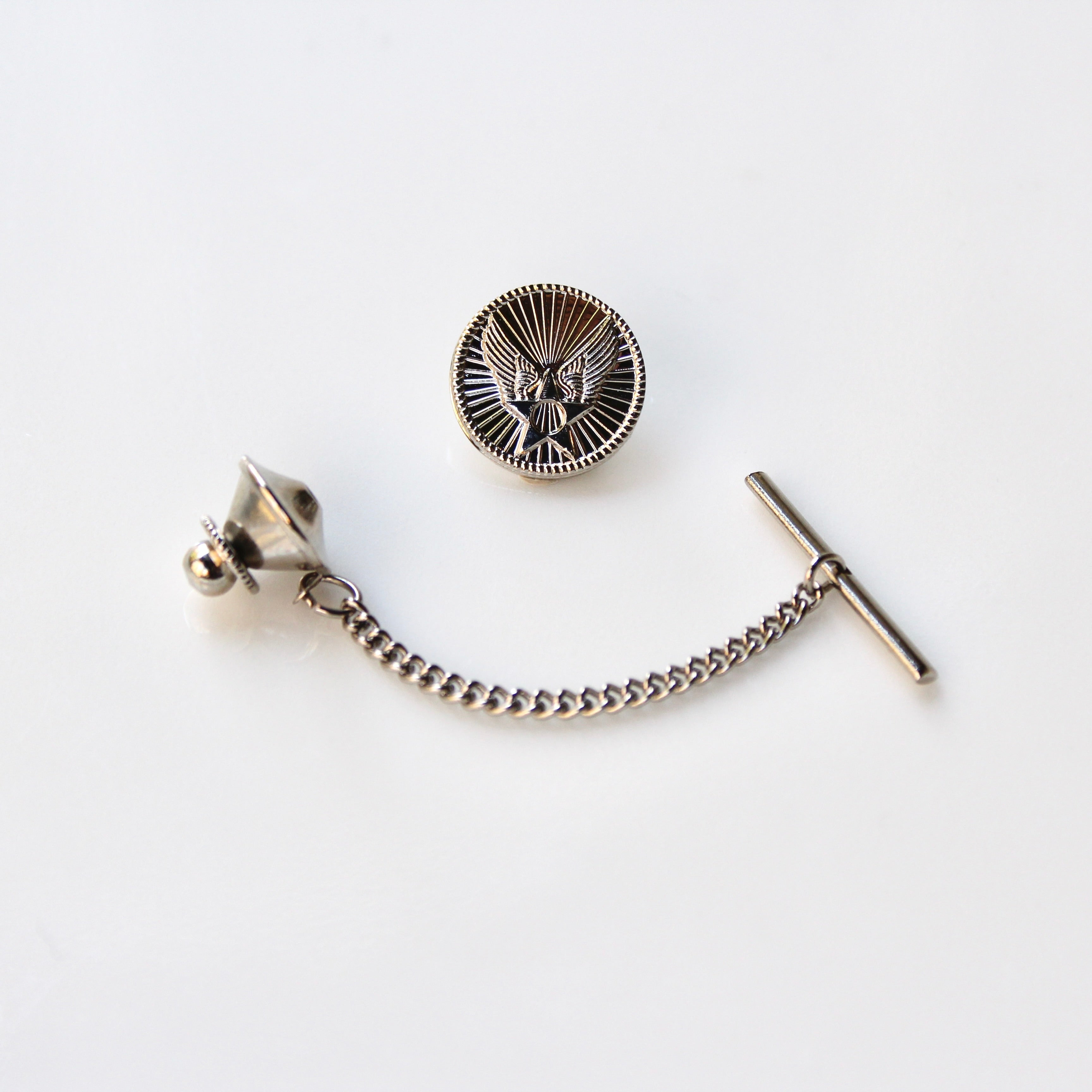 Silver tie pin with chain and eagle emblem on a white background