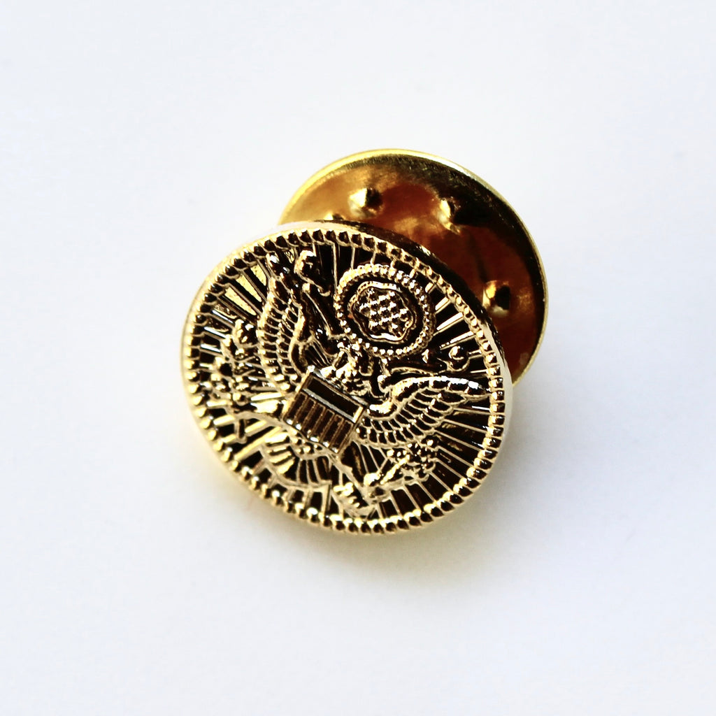 Gold pin with intricate design on a white background