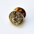 Gold pin with intricate design on a white background