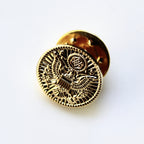 Gold pin with intricate design on a white background