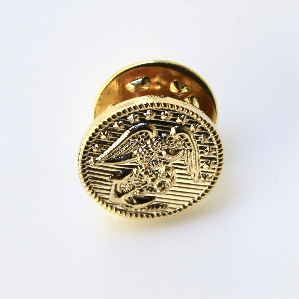Gold-colored lapel pin with an eagle design on a white background