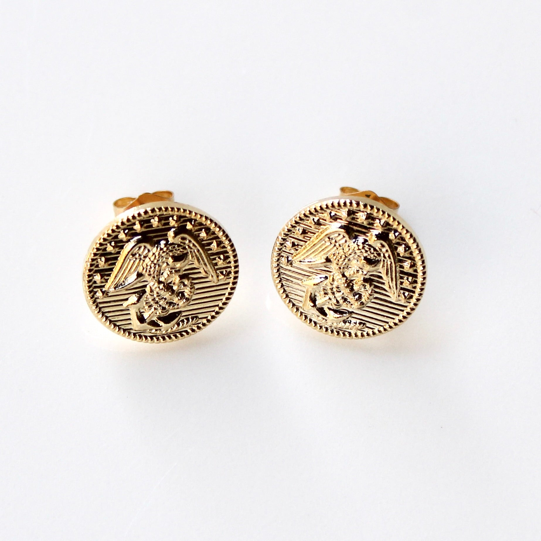 Gold circular earrings with an eagle design on a white background