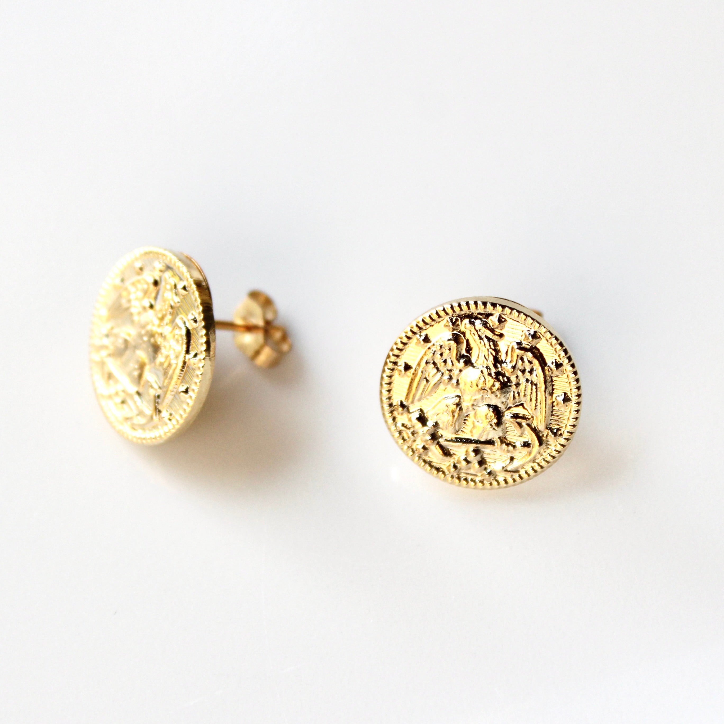 Gold coin-shaped earrings on a white background