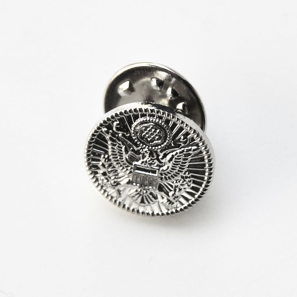 Silver metal badge with an eagle design on a white background