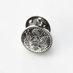 Silver metal badge with an eagle design on a white background