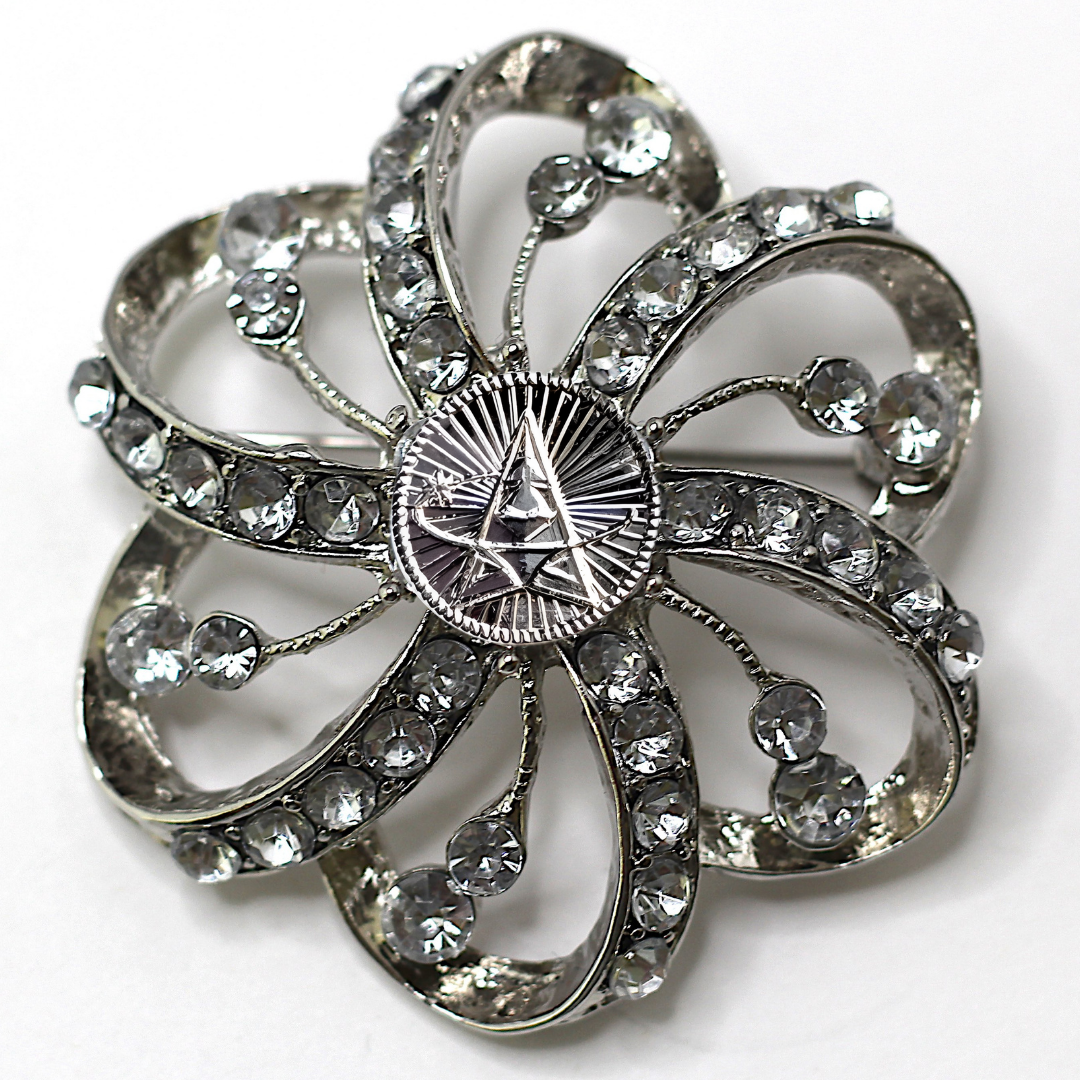 Silver flower-shaped brooch with clear gemstones and Space Force centerpiece on a white background