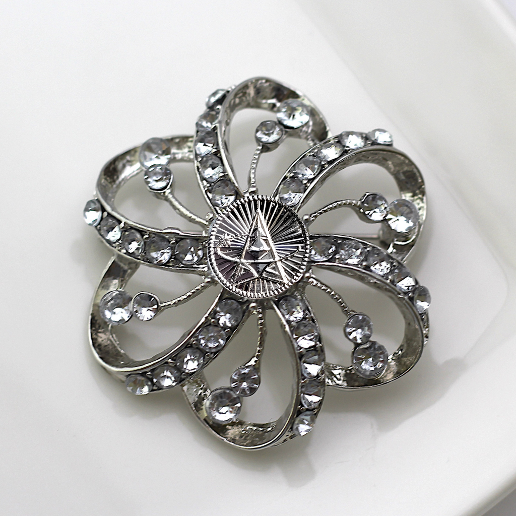 Silver flower-shaped brooch with clear gemstones and Space Force centerpiece on a white background