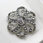 Silver flower-shaped brooch with clear gemstones and Space Force centerpiece on a white background