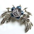 Decorative brooch with blue pearls and silver leaves on a white background
