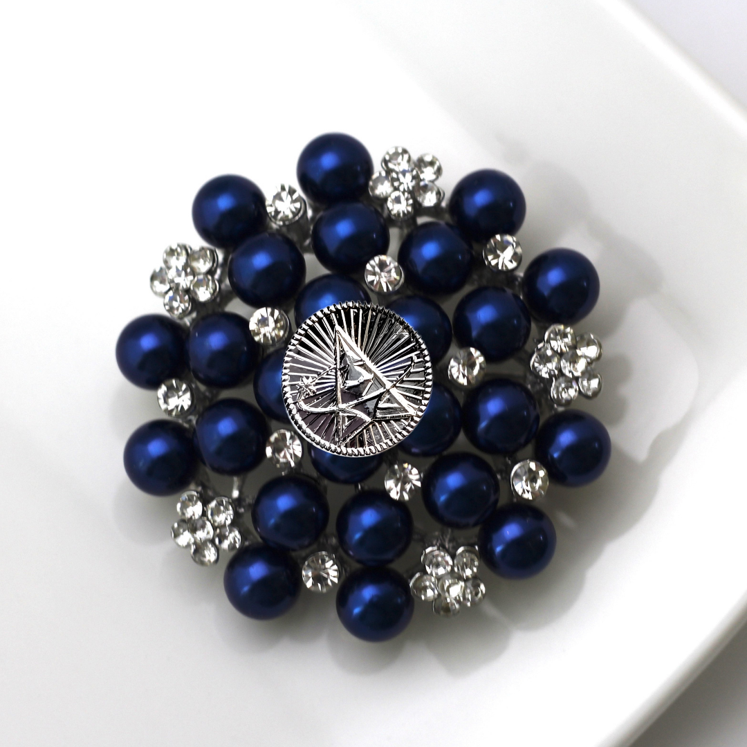 Brooch with blue pearls and silver accents on a white background