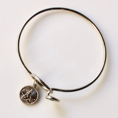 Silver bangle with a round charm on a light gray background