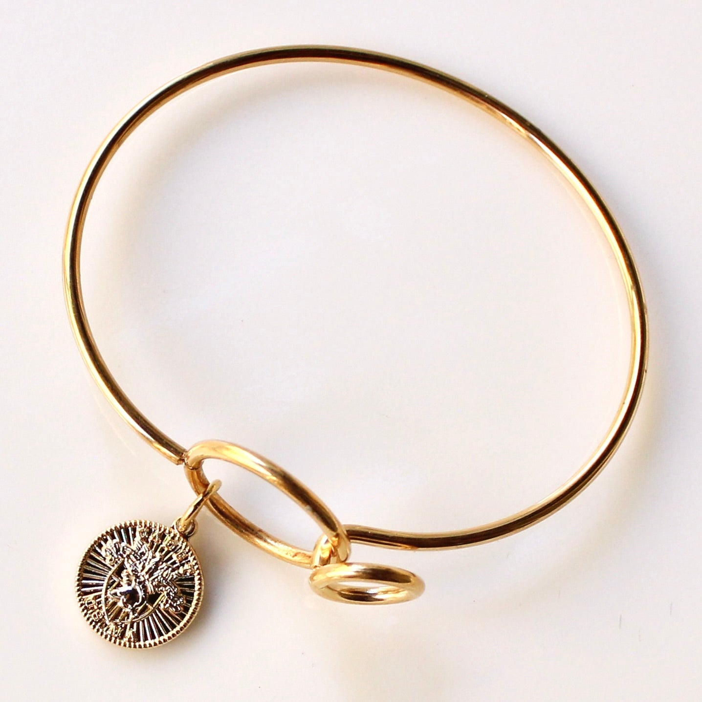 Gold bracelet with a circular charm on a white background