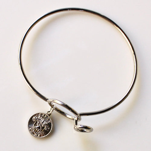 Silver bangle with a charm on a white background