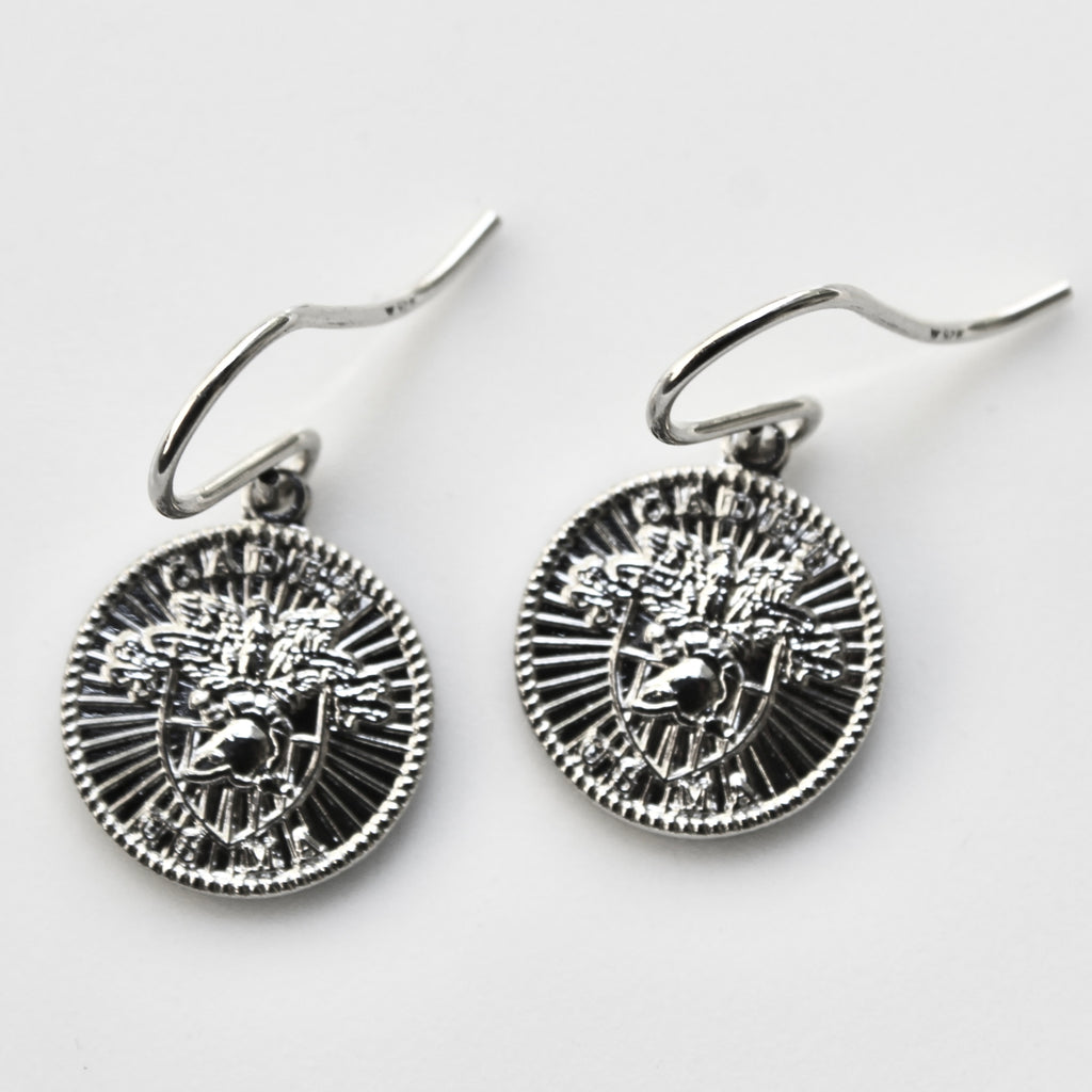 Pair of silver earrings with intricate designs on a light gray background