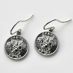 Pair of silver earrings with intricate designs on a light gray background