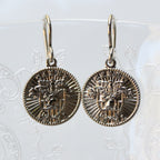 Pair of gold coin-shaped earrings on a white background