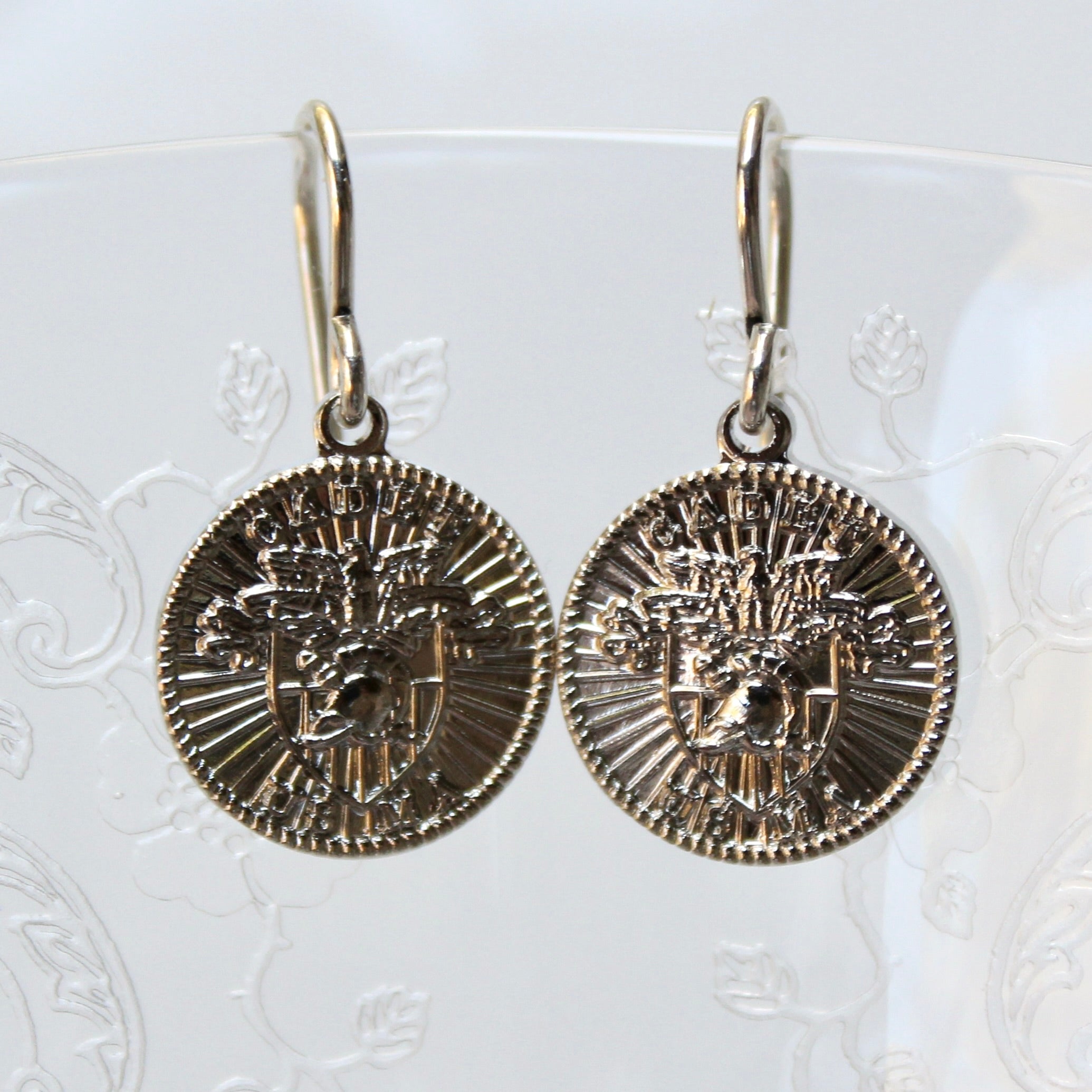 Pair of gold coin-shaped earrings on a white background