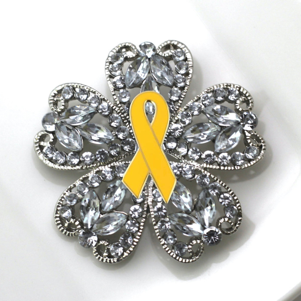 Brooch with a yellow ribbon and crystal-like design on a white background
