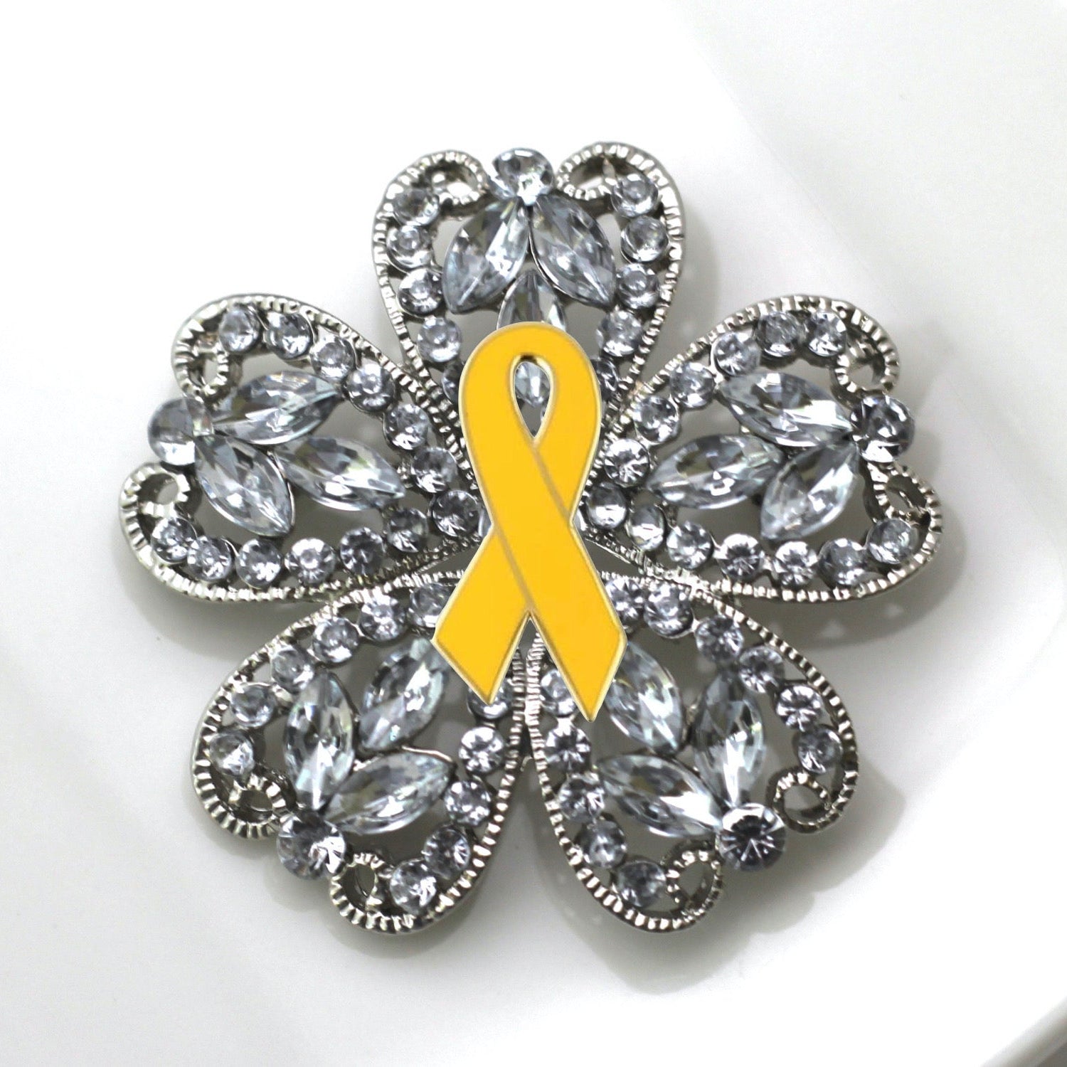 Brooch with a yellow ribbon and crystal-like design on a white background