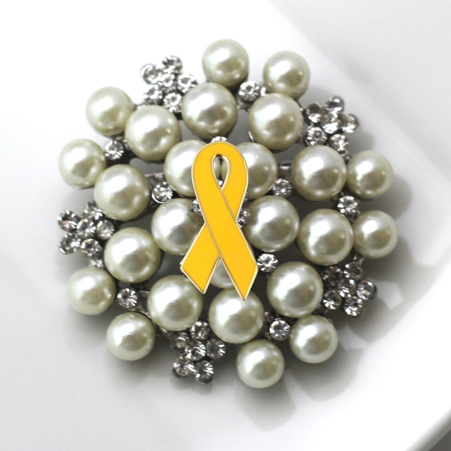 Pearl brooch with a yellow ribbon on a white background