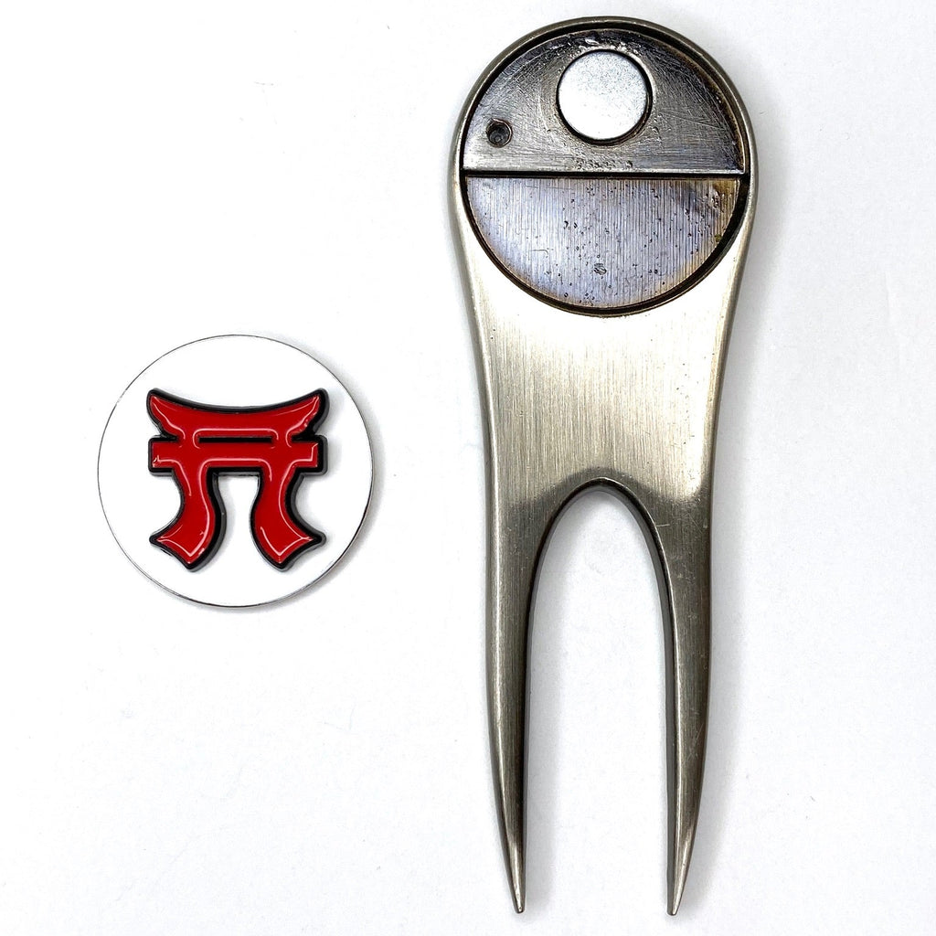 Metallic golf divot tool with a red and black logo on a white background