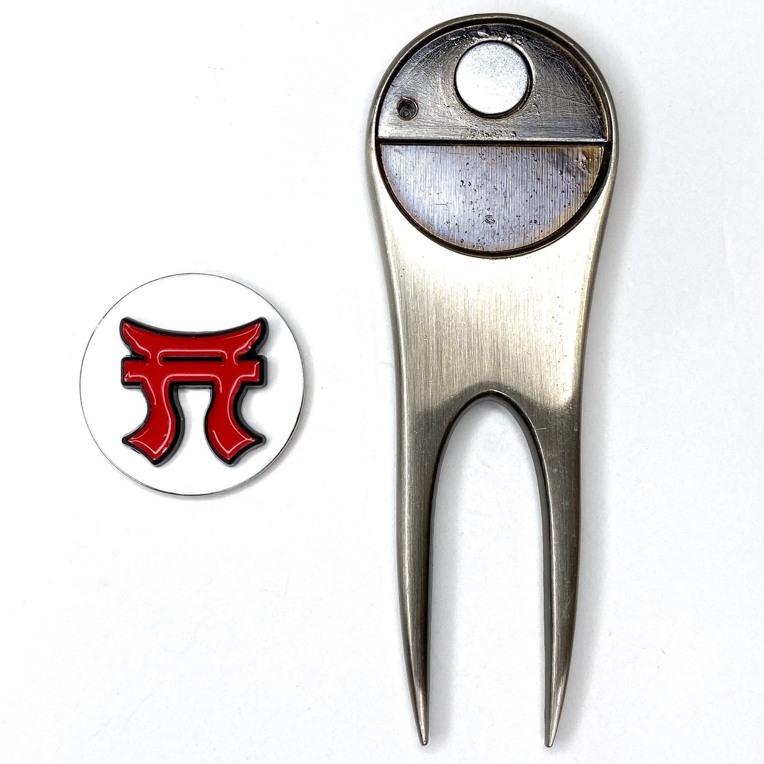 Metallic golf divot tool with a red and black logo on a white background