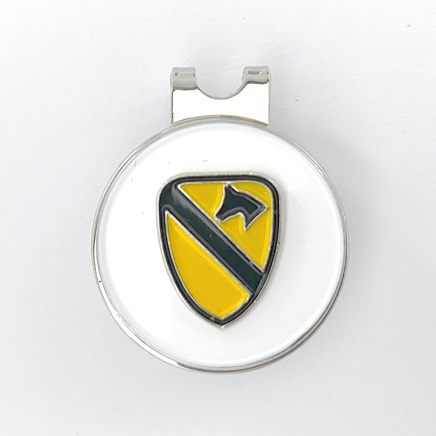 A yellow triangular golf hat clip with a black horse head and shield design, representing the 1st Cavalry Division.