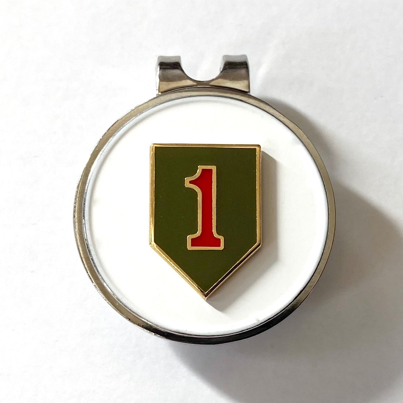 A golf hat clip with a magnetic ball marker featuring the 1st Infantry Division insignia, consisting of a red '1' on an olive drab shield, set against a white background.