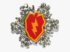 A silver brooch featuring a red taro leaf with a yellow lightning flash, surrounded by crystal embellishments.