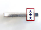 A tie clip with a blue star service flag design on a gold or silver metal clip with a red and white border.