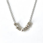 Silver necklace with letter beads on a white background