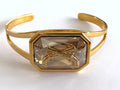 Gold cuff bracelet with a Swarovski crystal and crossed pistols insignia.