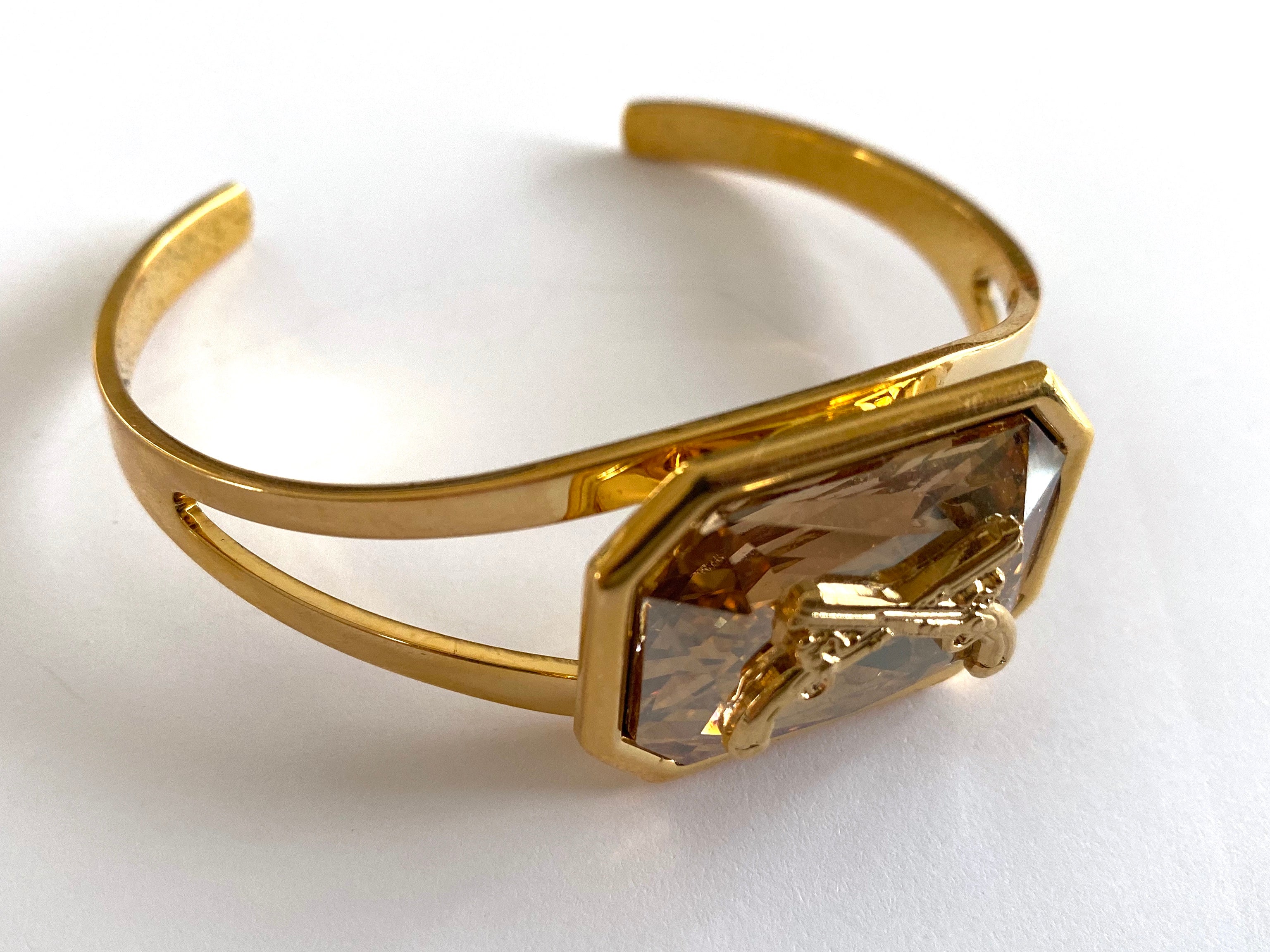 Gold cuff bracelet with a Swarovski crystal and crossed pistols insignia.