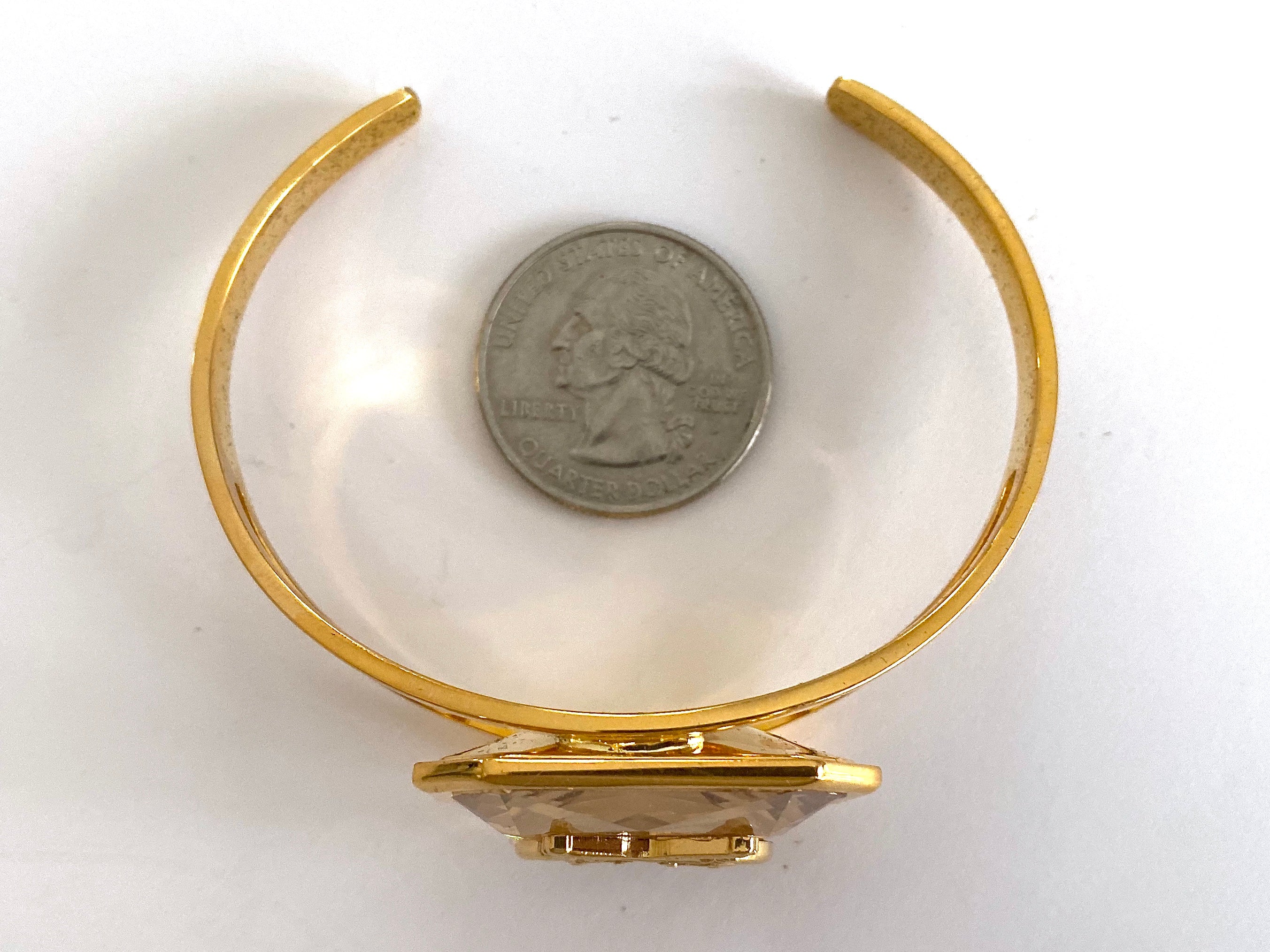 Gold cuff bracelet with a Swarovski crystal and crossed pistols insignia.