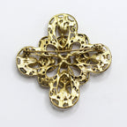 A vintage gold-tone filigree cross brooch with a pin back, displayed on a clean white background.