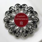 A custom-designed brooch with silver, black, and clear crystals, featuring a heraldic design, placed on a white surface with the brand name 'Hope Design Ltd.' visible.