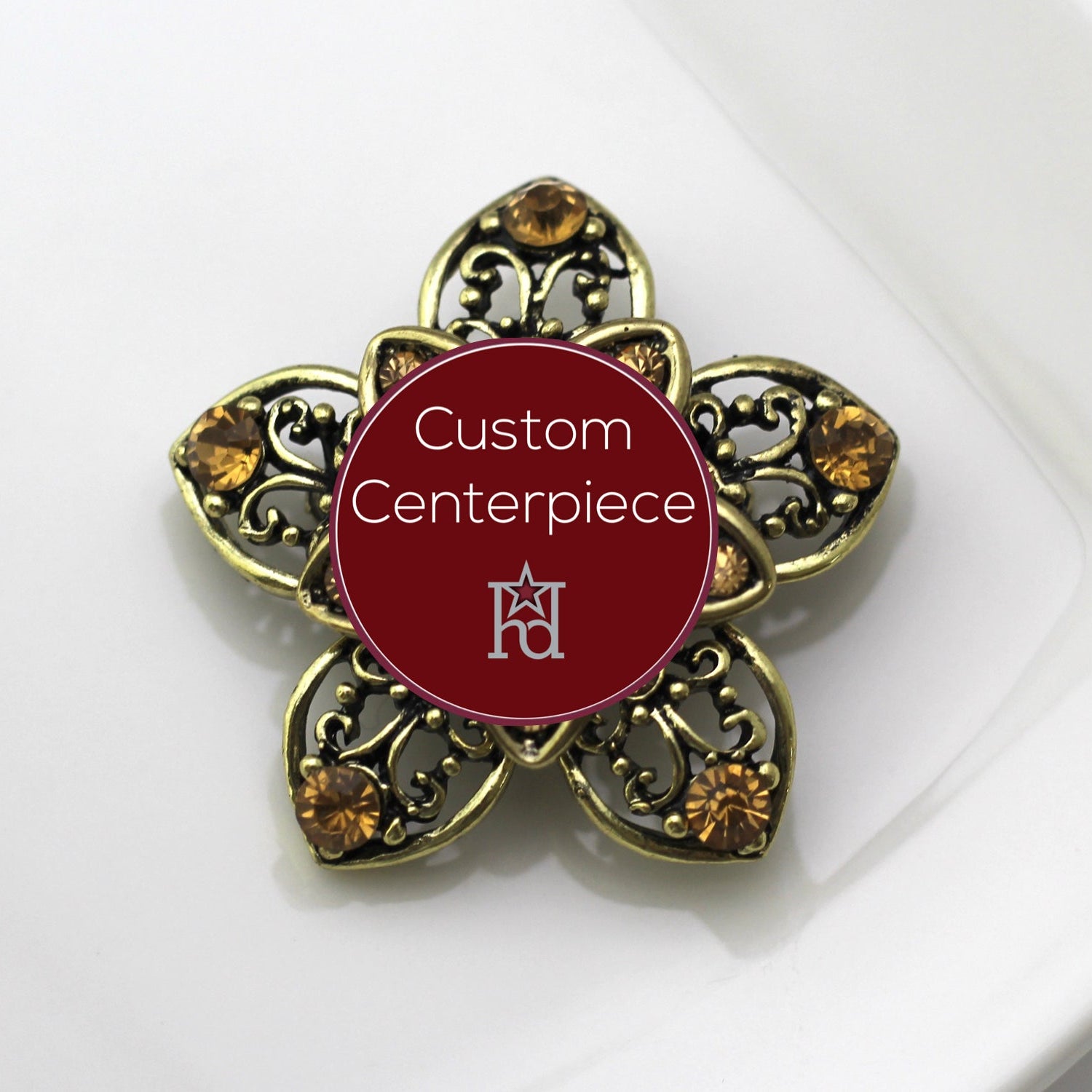 A gold brooch with topaz crystals and a custom centerpiece featuring military heraldry.