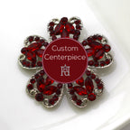 A silver brooch with red crystals designed as a flower, featuring a custom centerpiece with the logo of Hope Design Ltd.