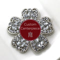 A silver brooch with clear crystal embellishments in a floral pattern with a central red label stating 'Custom Centerpiece'.