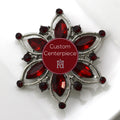A silver brooch with red crystals designed as a custom centerpiece, displayed on a white plate.