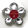 A custom-designed brooch with silver and clear crystals, featuring a floral pattern and a central 23K insignia emblem.