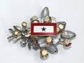 Vintage brooch with a blue star and red background, encircled by clear crystals and silver-colored metal accents.