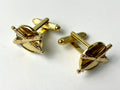 A set of gold-colored men's accessories with military insignia, including cufflinks and a tie bar.