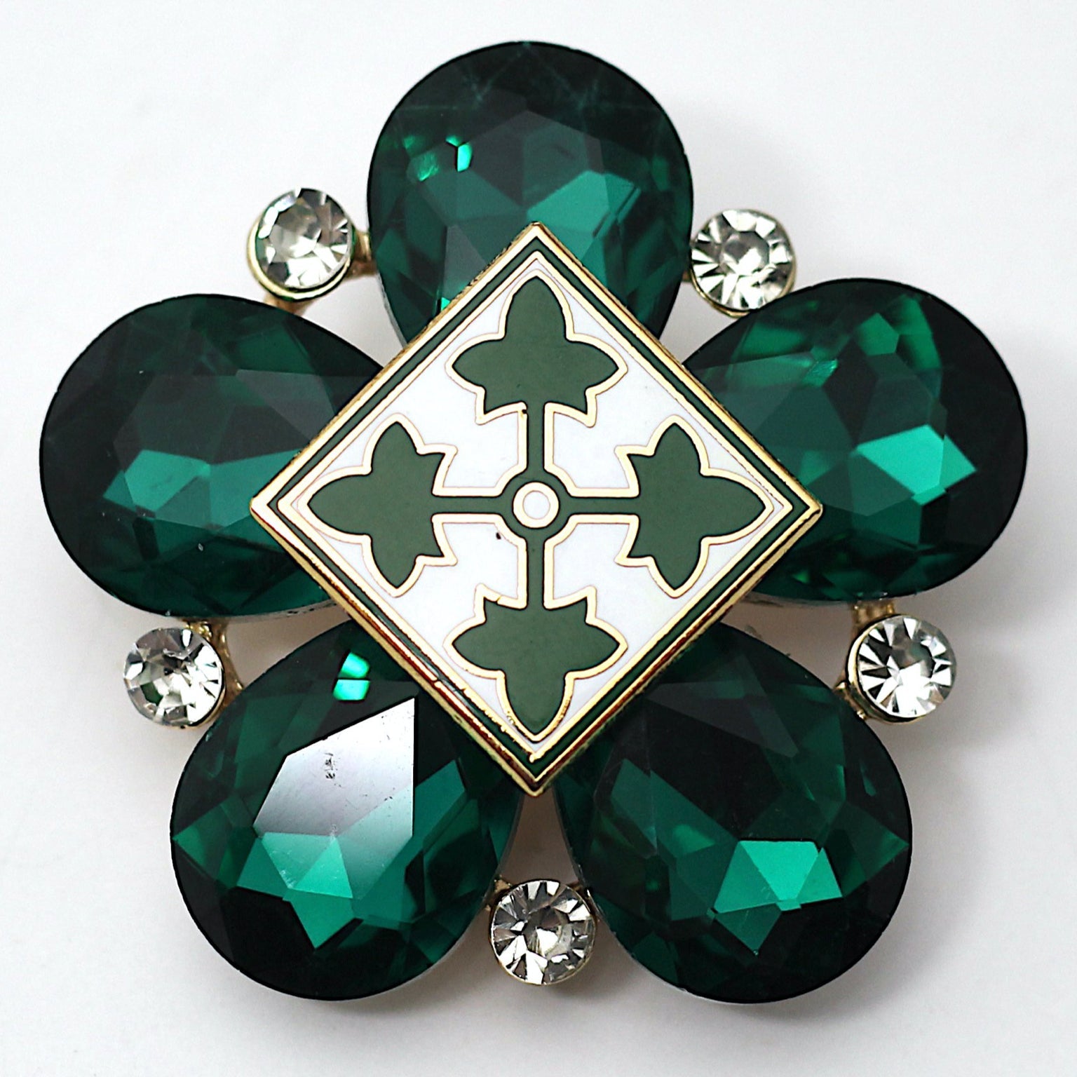 A limited edition brooch featuring a green, geometric-shaped insignia with a '4ID' emblem in the center surrounded by green rhinestones and smaller white and black stones along the perimeter.