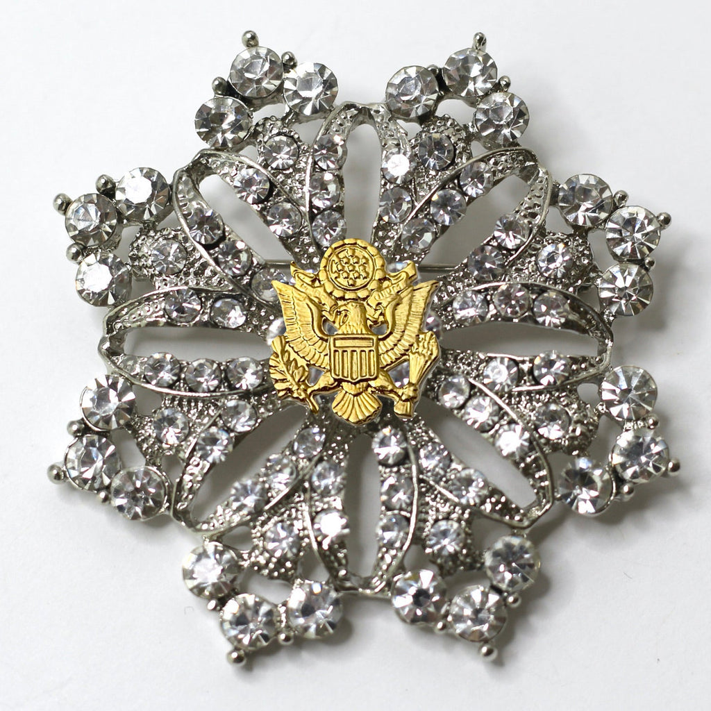 A silver brooch featuring a central eagle motif surrounded by crystal rhinestones, with a patriotic theme.