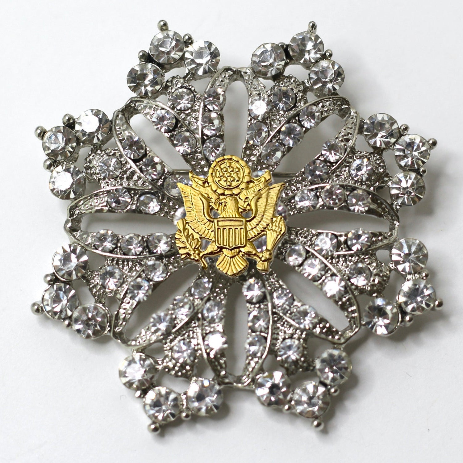 A silver brooch featuring a central eagle motif surrounded by crystal rhinestones, with a patriotic theme.