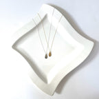 Two necklaces on a white dish with a white background