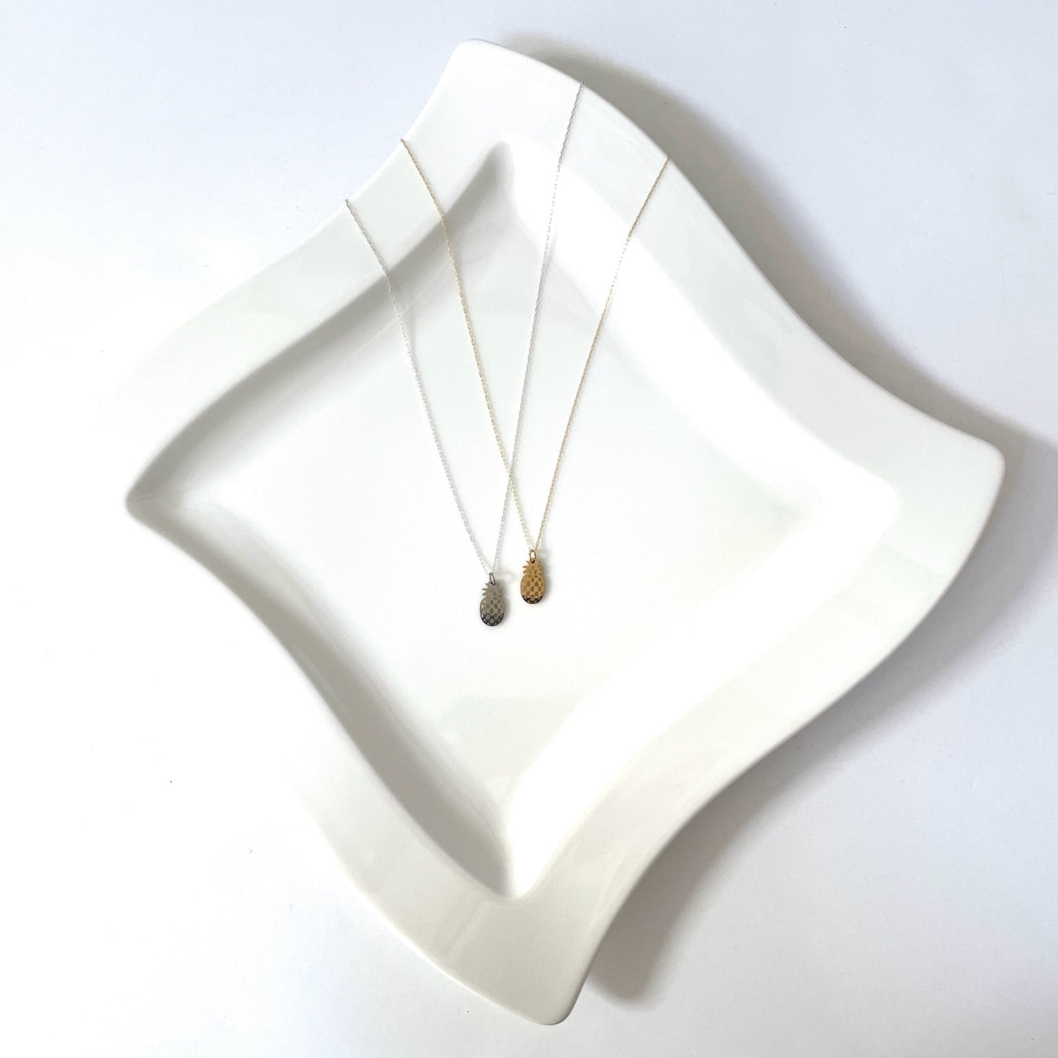 Two necklaces on a white dish with a white background